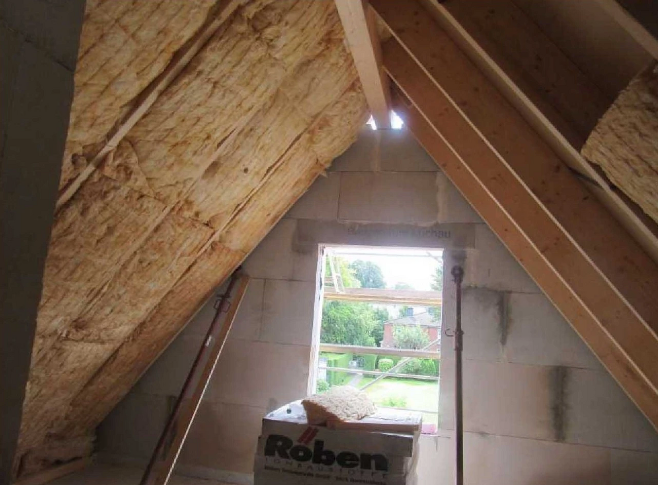 Dachausbau mit Dämmmaterial und Blick durch Fenster.